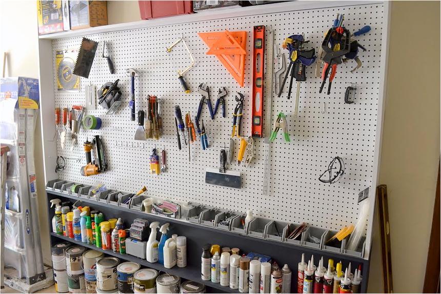 A white pegboard with tools in a garage