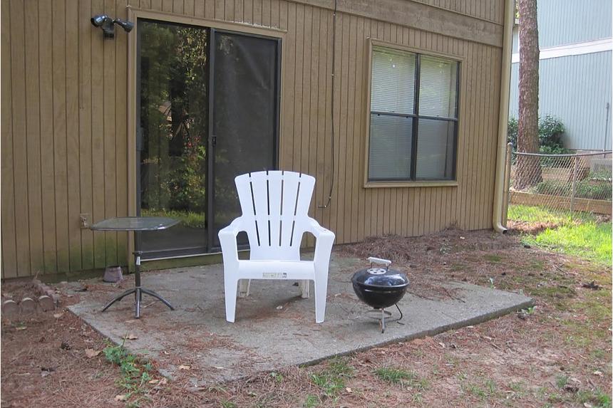 A concrete slab outside a sliding door with a white chair