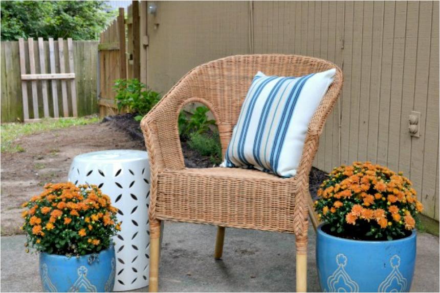 A wicker chair on a concrete slab with two blue pots