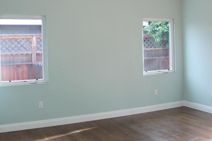 Empty bedroom with teal painted walls and dark wood floors