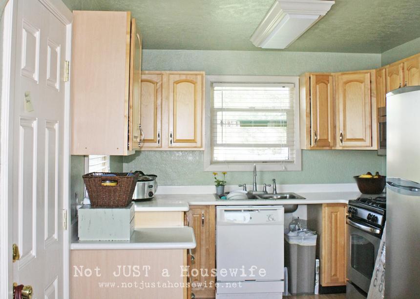 Outdated kitchen with teal walls and wood cabinetry