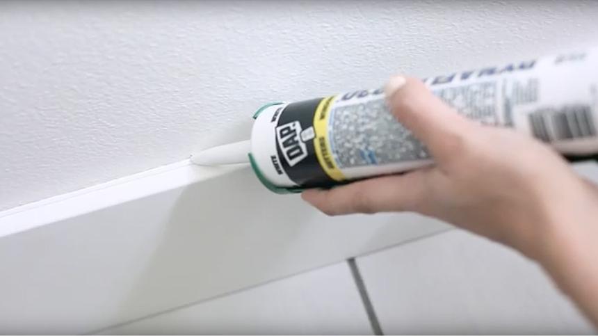 Woman applying caulk to a wall
